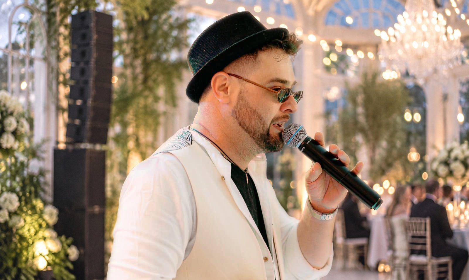Fotomontaggio: il cantante canta al microfono in un'orangerie illuminata per un matrimonio serale